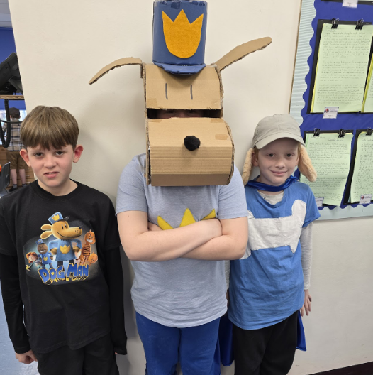 3 students in DogMan costumes, smiling